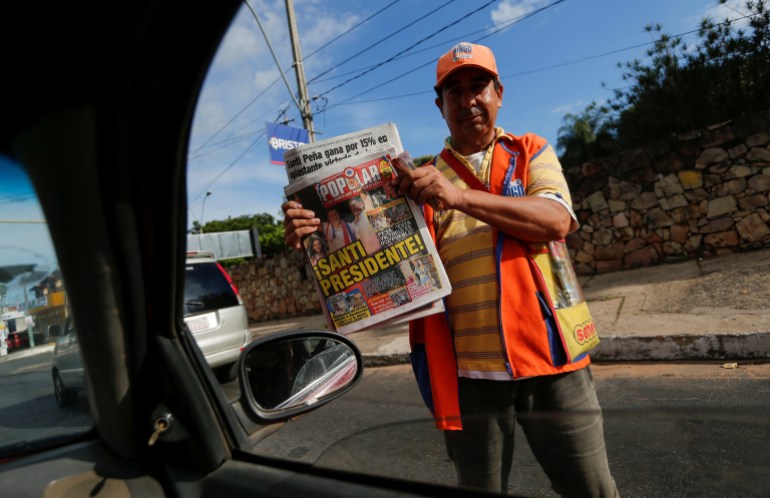 A seller holds a newspaper announcing Santiago Pena as Paraguay's next president