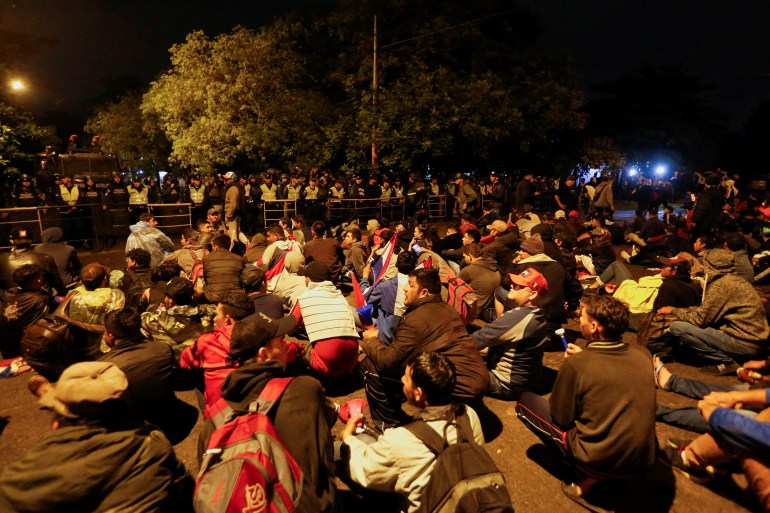 Persone sedute per terra fuori al buio ad Asuncion, Paraguay