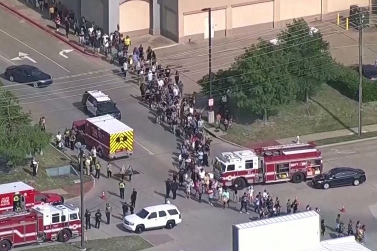 Shoppers leave as law enforcement officers respond to a shooting in the Dallas area's Allen Premium Outlets in a still taken from aerial video. Hundreds of people can be seen streaming from the mall in a line. Many emergency workers and vehicles are on the scene.