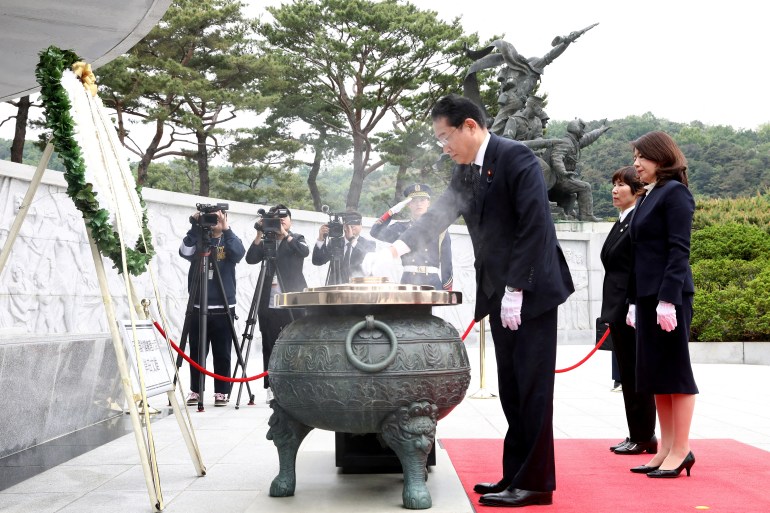 Japanese Prime Minister Fumio Kishida burns incense as his wife Yuko stands during a visit to National Cemetery