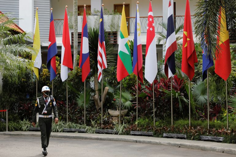 A soldier walks past ASEAN flags at the venue in Labuan Bajo