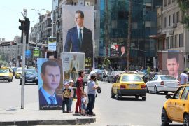People stand near posters depicting Syria's President Bashar al-Assad, ahead of the May 26 presidential election