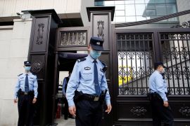 Police outside a court in Beijing. There are three of them and they're wearing pale blue uniforms. The court building is granite with gates.