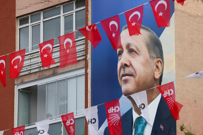 Turkish flags flutter in front of a poster of Turkish President Tayyip Erdogan ahead of the May 14 presidential and parliamentary elections