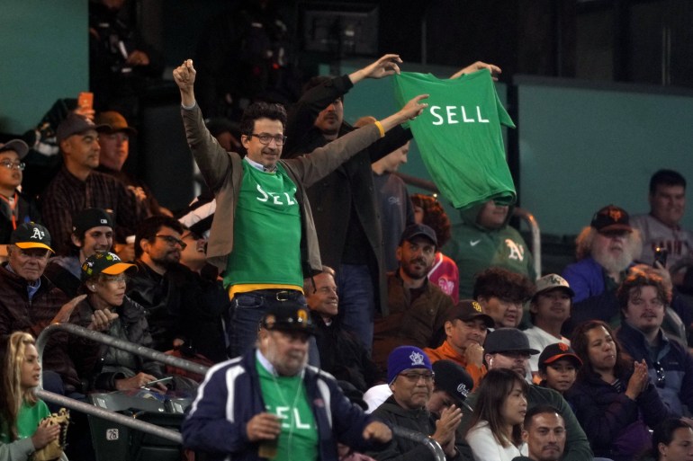 Athletics fans display shirts directed at management