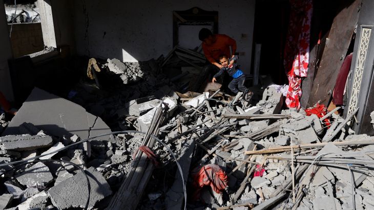 A man picks up a child at the site of an Israeli airstrike amid Israel-Gaza fighting in Deir al-Balah town in the central Gaza Strip, May 13, 2023. REUTERS/Ibraheem Abu Mustafa
