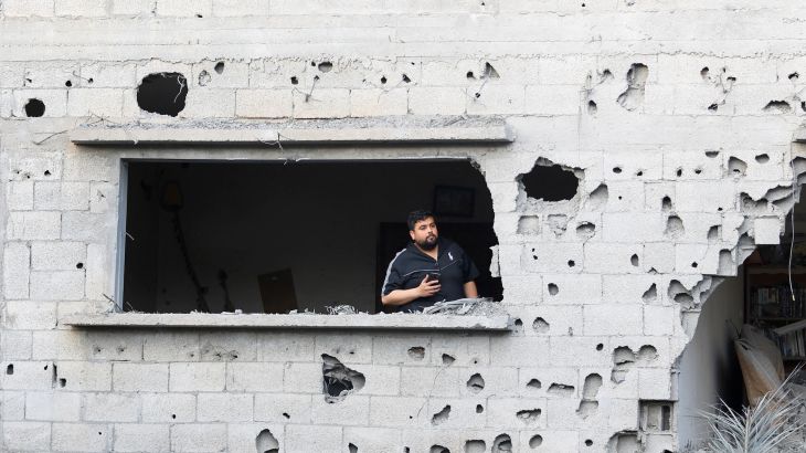 A Palestinian man stands in the window opening of the site of an Israeli air raid amid Israel-Gaza fighting in Deir al-Balah town in the central Gaza Strip.