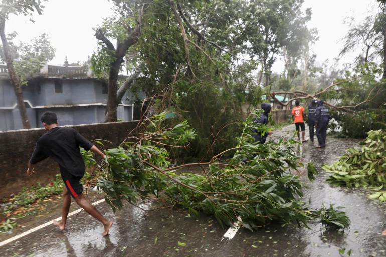 People move fallen trees from a road at Shah Porir Dwip after the landfall of cyclone Mocha in Teknaf, Bangladesh