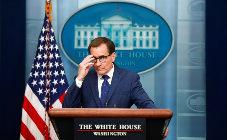 John Kirby adjusts his glasses on the podium in the White House press room
