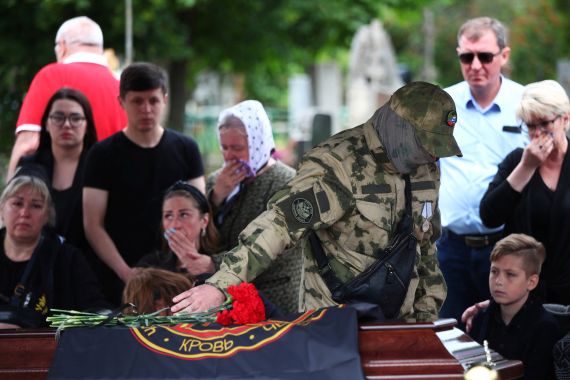 Un combattente della compagnia militare privata russa Wagner Group depone fiori sulla bara del suo compagno Yuri Kasukhin, ucciso durante il conflitto Russia-Ucraina, in un cimitero di Volgograd, Russia, 21 maggio 2023. REUTERS/Stringer