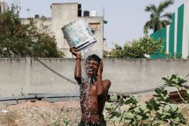 A boy bathes outside his residence on a hot summer day in New Delhi, India, May 22, 2023.