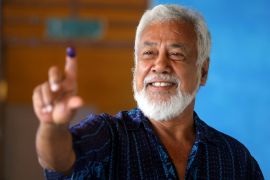 Xanana Gusmao holding up his ink-stained finger after voting. He is smiling.