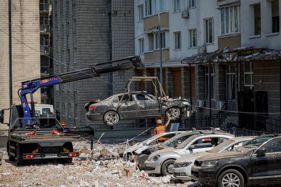 Cars damaged by falling debris being removed from the car park at a block of flats in Kyiv. One is in the air being transferred to a lorry.