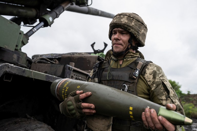 A Ukrainian service member of the 55th Separate Artillery Brigade prepare carries a shell for a Caesar self-propelled howitzer