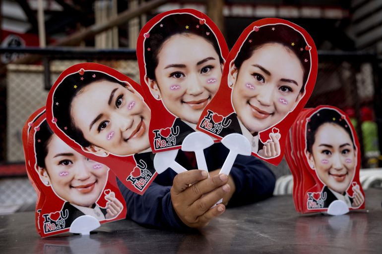 A supporter holds up fans printed with the face of Paetongtarn Shinawatra