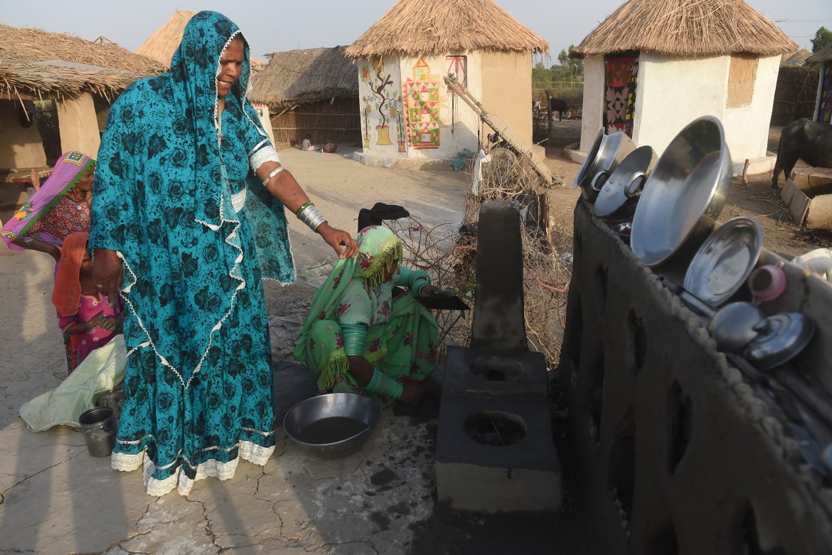 In this picture taken on April 8, 2023, Champa (L), a master trainer in making earthen stoves lifted off the floor, trains a woman at Sanjar Chang village