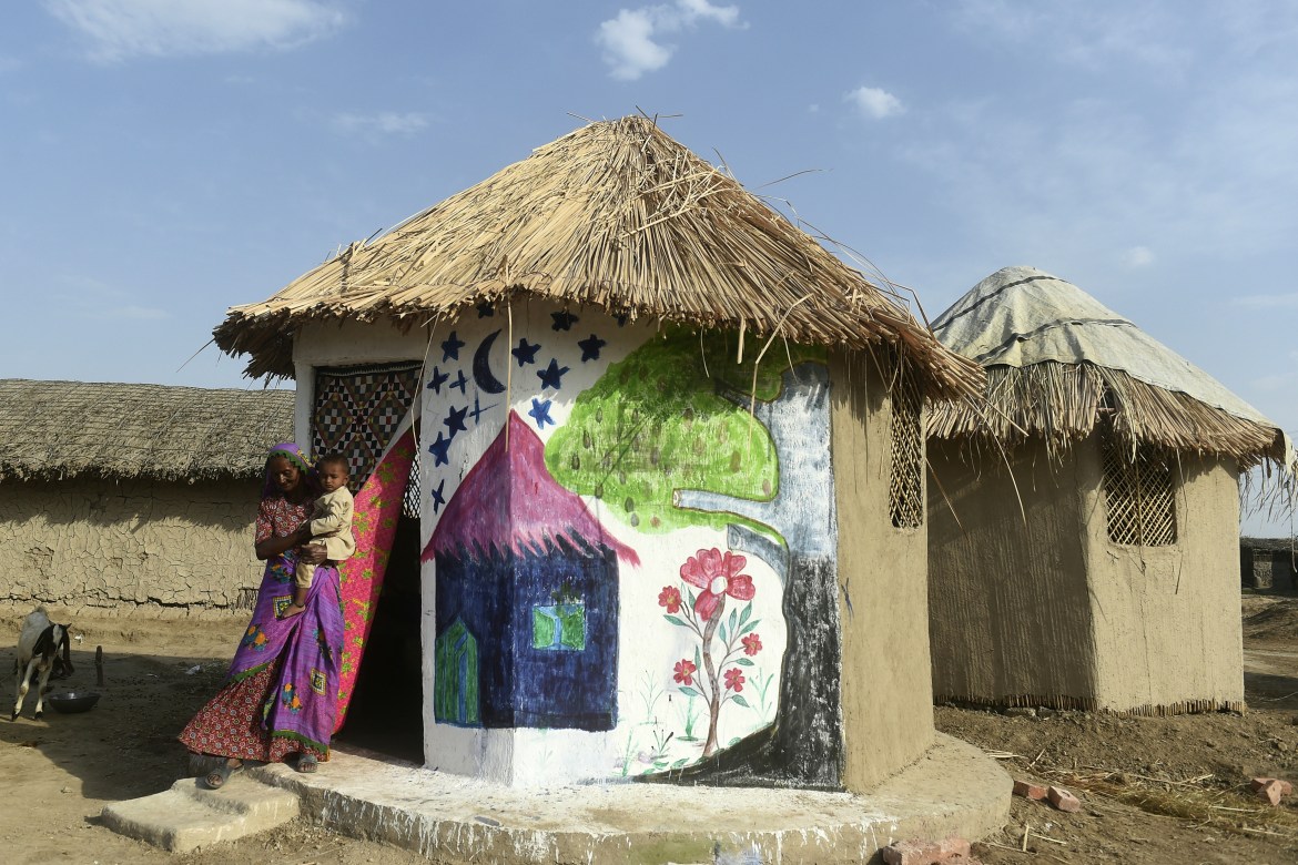 In this picture taken on April 8, 2023, Champa Chanbeli, who trains others to make earthen stoves lifted off the floor, comes out from her flood-resistant hut at Sanjar Chang village