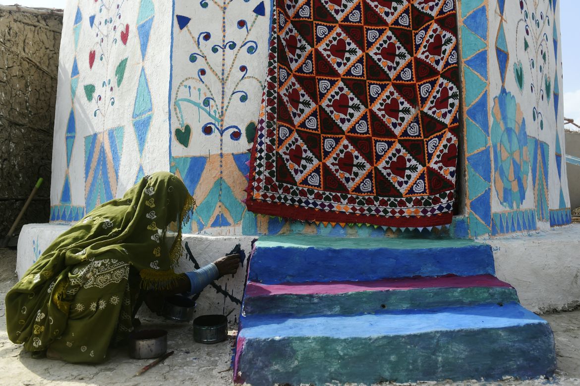 In this picture taken on April 8, 2023, a woman paints her flood-resistant hut at Sanjar Chang village