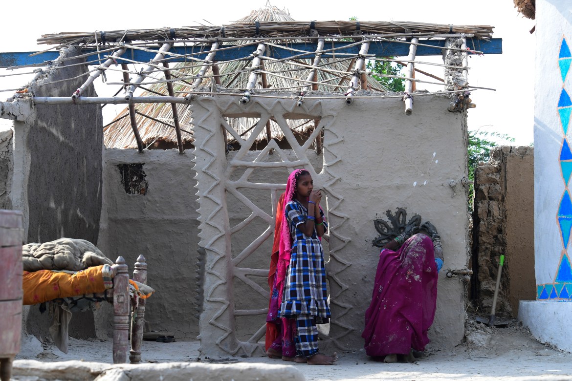 In this picture taken on April 8, 2023, a woman makes a floral o ament on a wall of her under construction flood-resistant hut at Sanjar Chang village