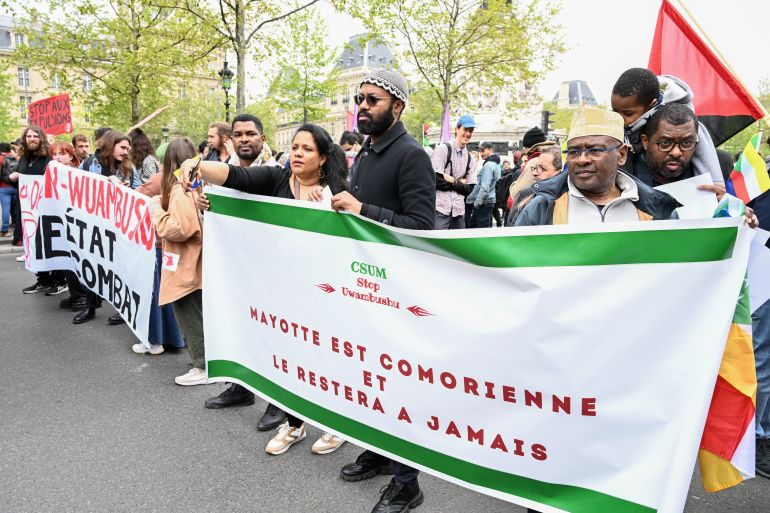 Protesters marching behind a banner reading "Mayotte is Comorian et will stay forever", take part in a demonstration against the French Minister of Interior, Gerald Darmanin's legislative proposal on asylum and immigration, in Paris, on April 29, 2023