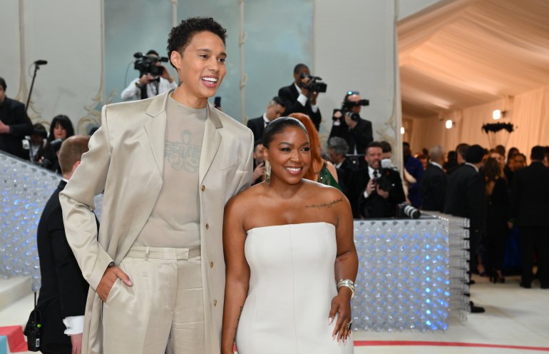 Brittney Griner and her wife Cherelle at the Met Gala, Brittney wearing a beige metallic suit and Cherelle wearing a white dress.