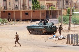 Sudanese Army sodliers walk near armoured vehicles stationed on a street in southern Khartoum