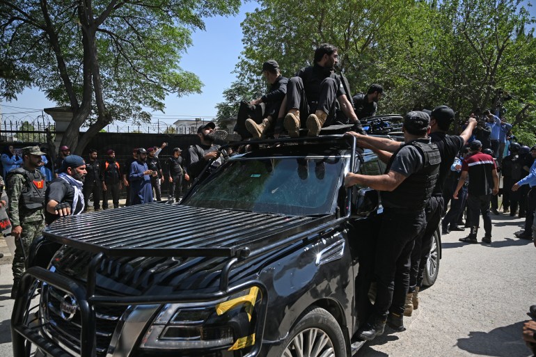 Security personnel escort a car carrying Pakistan's former Prime Minister Imran Khan as he arrives at the high court in Islamabad