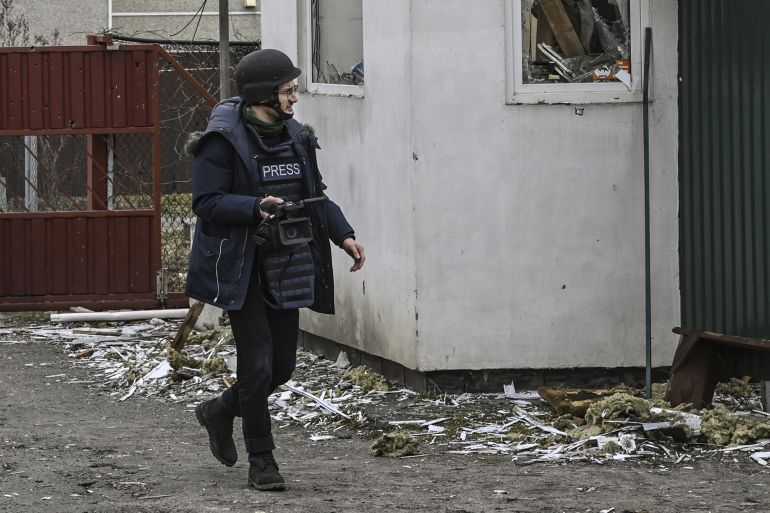 AFP journalist Arman Soldin walking in a Ukrainian village after shelling last month. There is debris on the ground. He is wearing a helmet and body armour identifying him as media.
