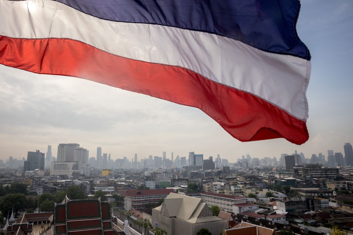 A Thai flag flying over the Bangkok skyline.