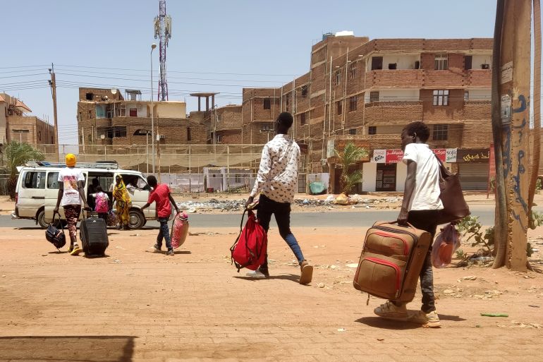 People carrying luggage prepare to board a minibus as they evacuate southern Khartoum, on May 14, 2023.