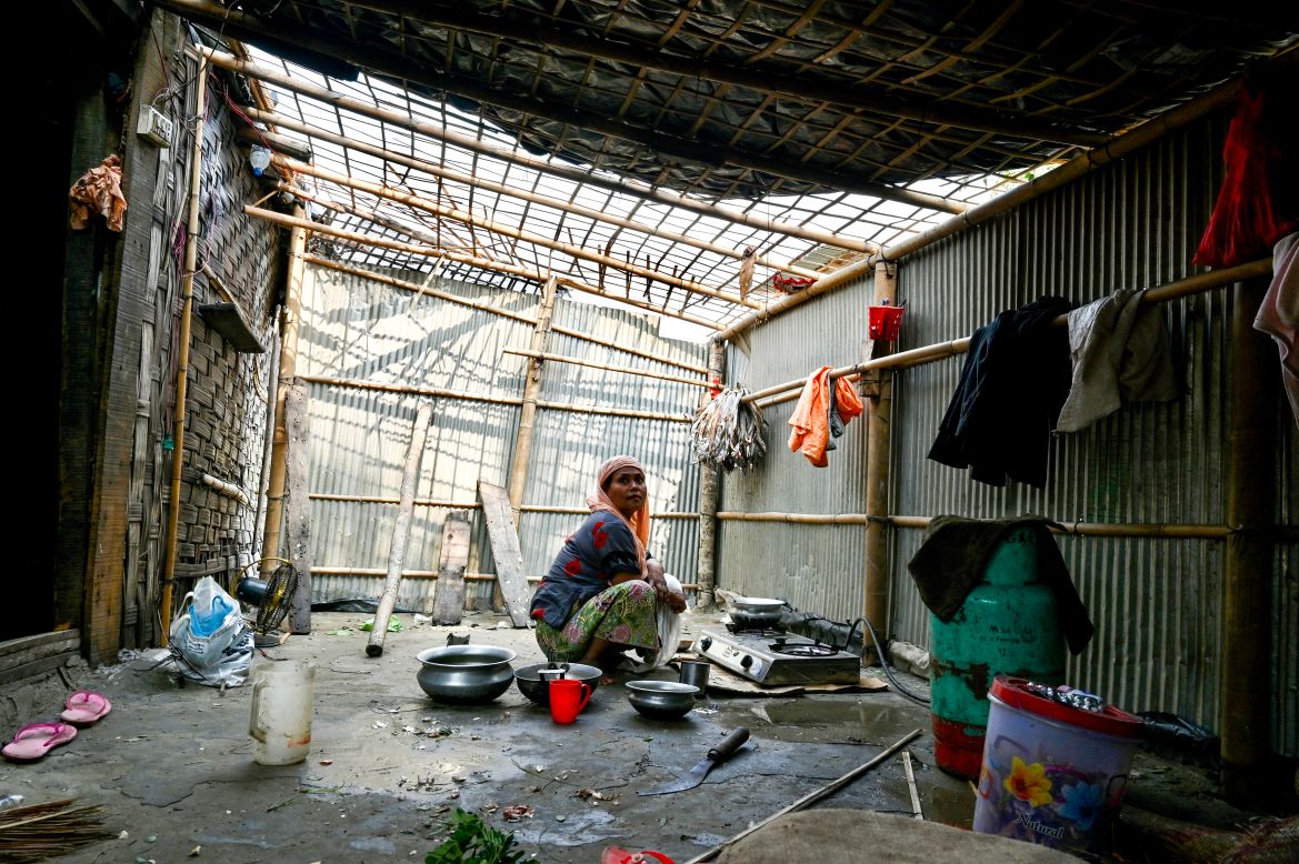 A woman cooks inside her house which was partially destroyed by cyclone Mocha, in Shahpori island on the outskirts of Teknaf