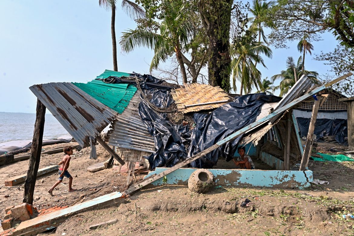 A boy walks beside a house which was partially destroyed by cyclone Mocha, in Shahpori island on the outskirts of Teknaf