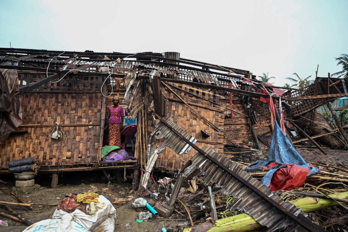 A Rohingya woman stands in her damaged house at Basara refugee camp in Sittwe