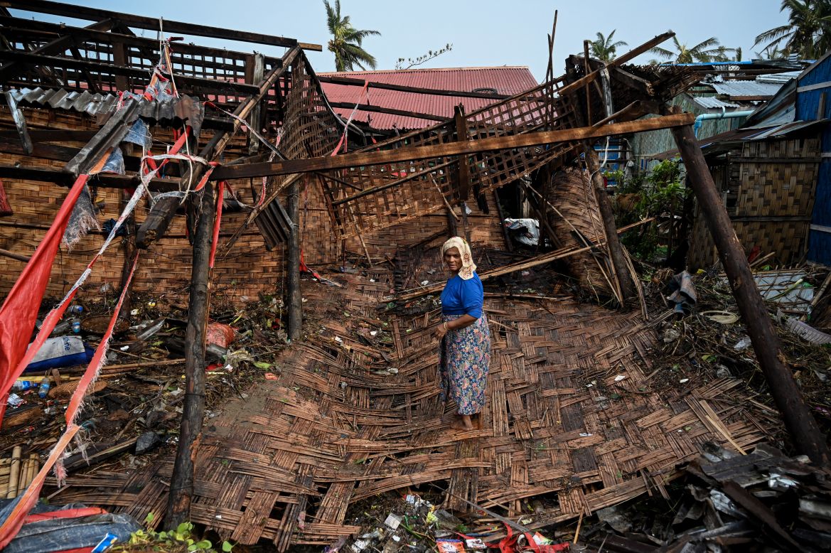 A Rohingya woman stands in her destroyed house at Basara refugee camp in Sittwe