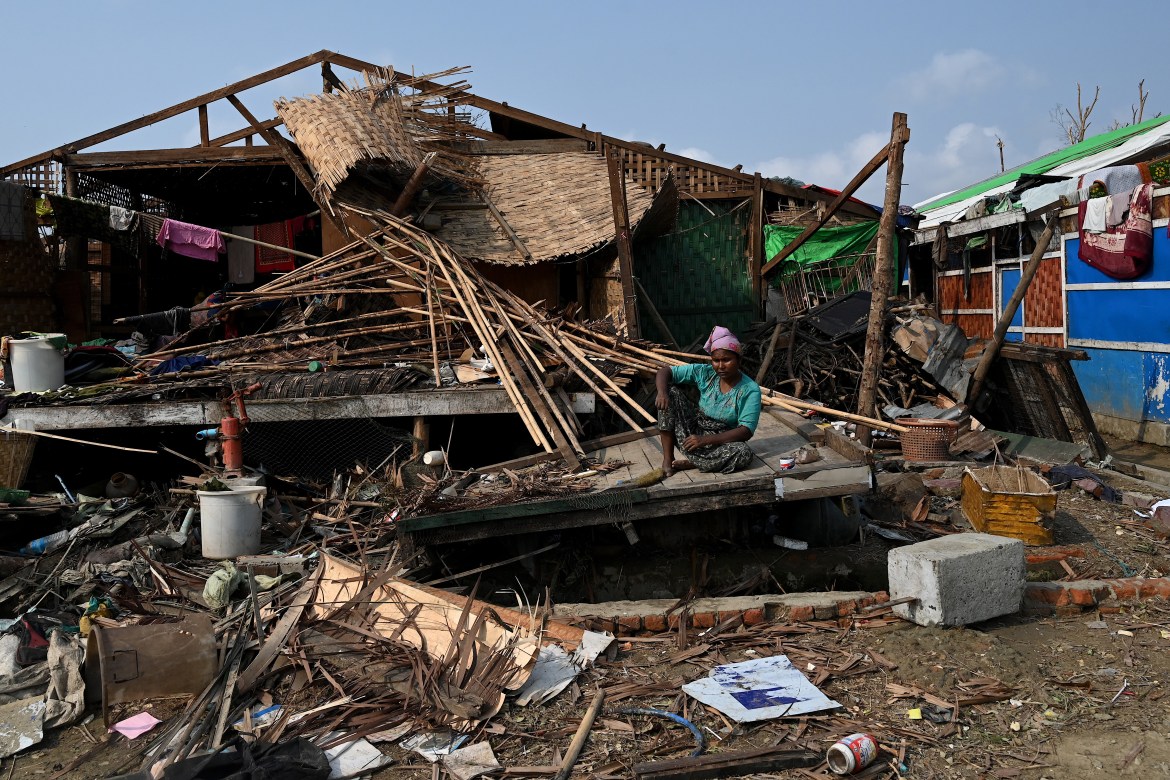 A Rohingya woman sits by her destroyed house at Ohn Taw Chay refugee camp in Sittwe