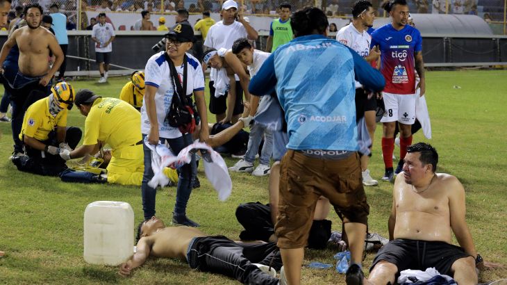 Supporters are helped by others following a stampede during a football match between Alianza and CD FAS at Cuscatlan stadium in San Salvador