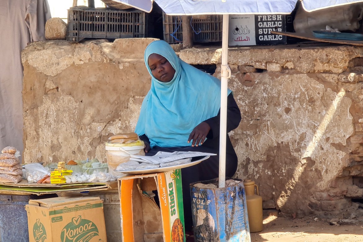 A woman sells foodstuffs at a stall on a market street in southern Khartoum