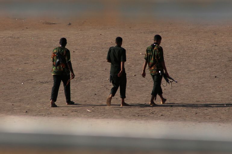 Armed men walk in Khartoum