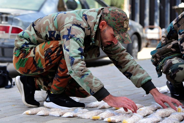 um soldado sírio exibe pílulas Captagon em uma calçada