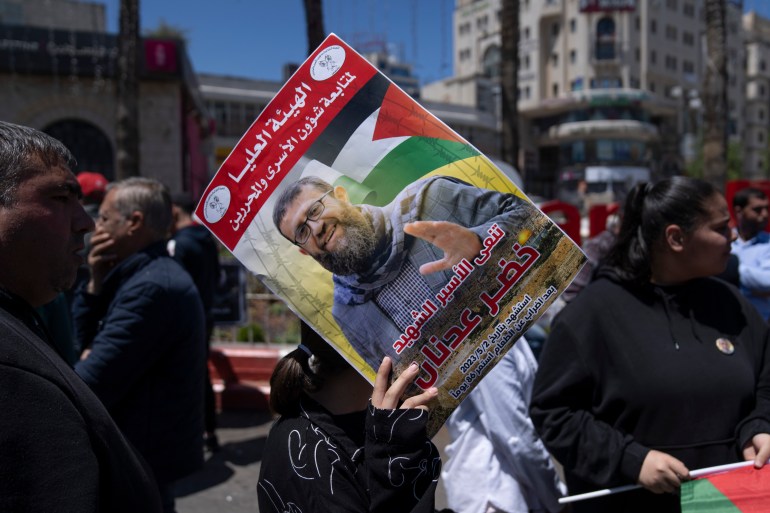 A Palestinian woman holds a poster with a photo of Khader Adnan during a protest in the West Bank city of Ramallah