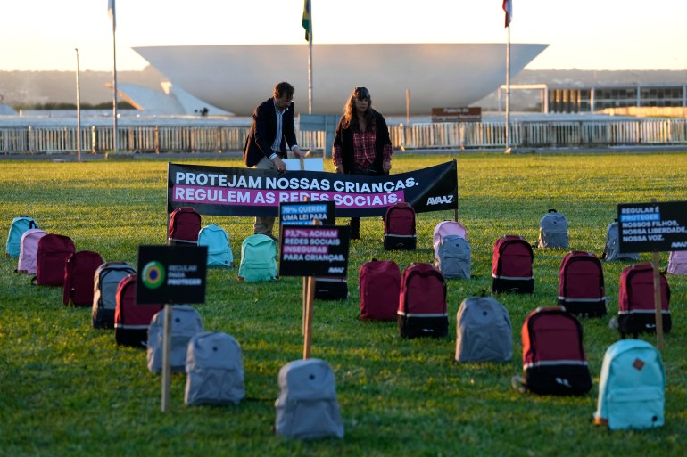Protesters outside Brazil's Congress place signs and backpacks on the grass to represent children killed in school bombings