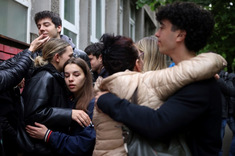 People comfort each other at a memorial to those who died in a school shooting in Belgrade.