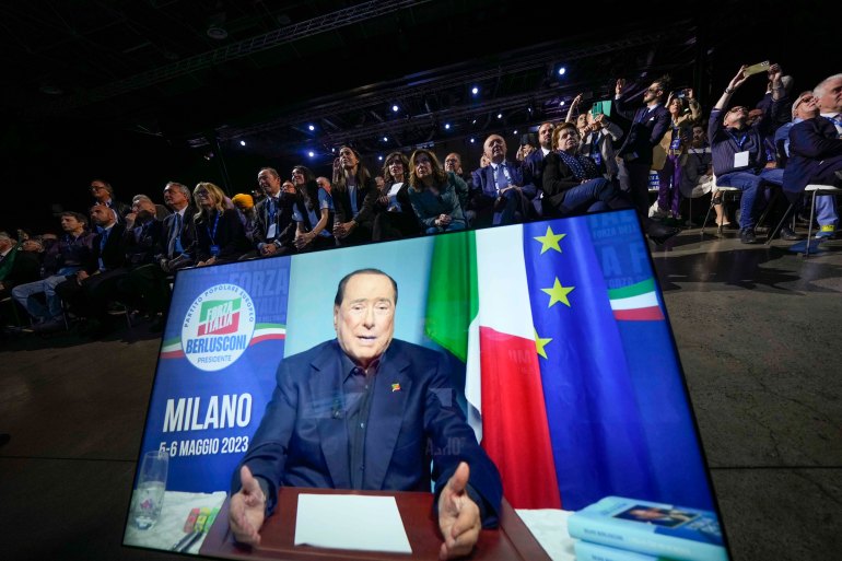 Forza Italia party activists watch Silvio Berlusconi as he talks in his video address during a Forza Italia party convention in Milan