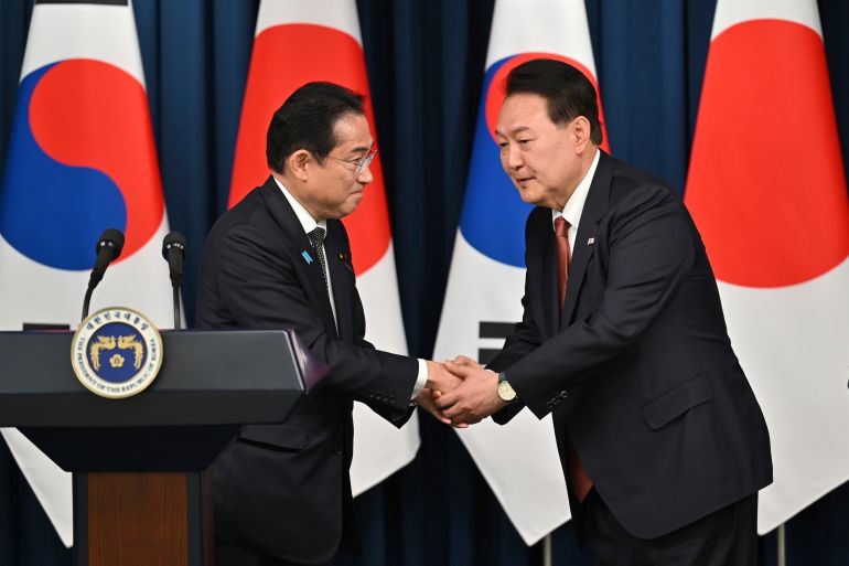 South Korean President Yoon Suk Yeol, right, shakes hands with Japanese Prime Minister Fumio Kishida during a joint press conference after their meeting at the presidential office in Seoul
