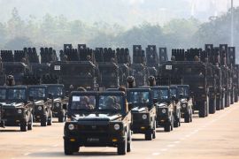 A military parade in Naypyidaw. Military officers are in rows of jeeps in front with weaponry in vehicles behind