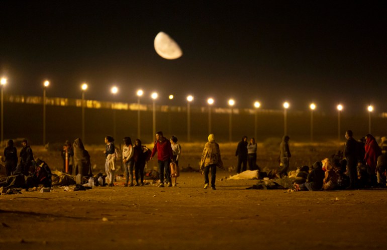 Migrants arrive at a gate in the border fence