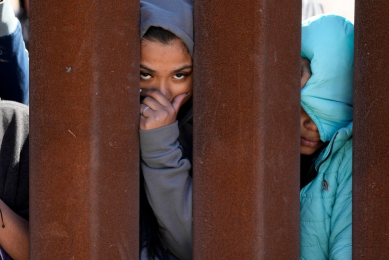 Migrants awaiting asylum peeking through the wall between the two border walls