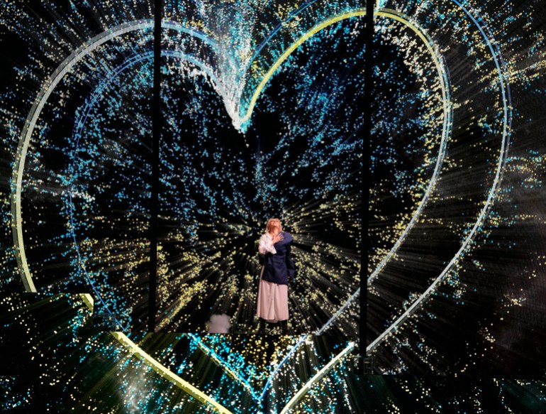 Ukrainian singer Alyosha performs in front of two handdrawn hearts in blue and yellow of Ukraine