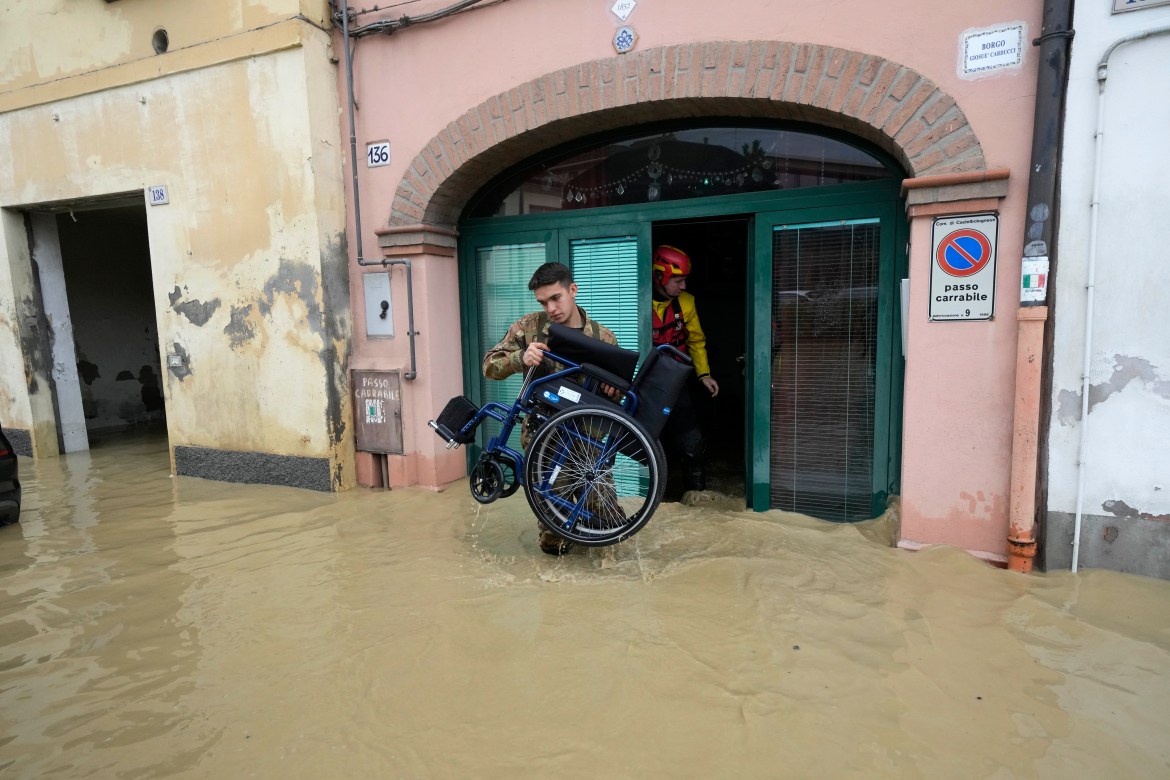 A soldier carries a wheelchair during a rescue operation in the flooded village of Castel Bolognese, Italy, Wednesday, May 17, 2023 [Luca Bruno/AP]