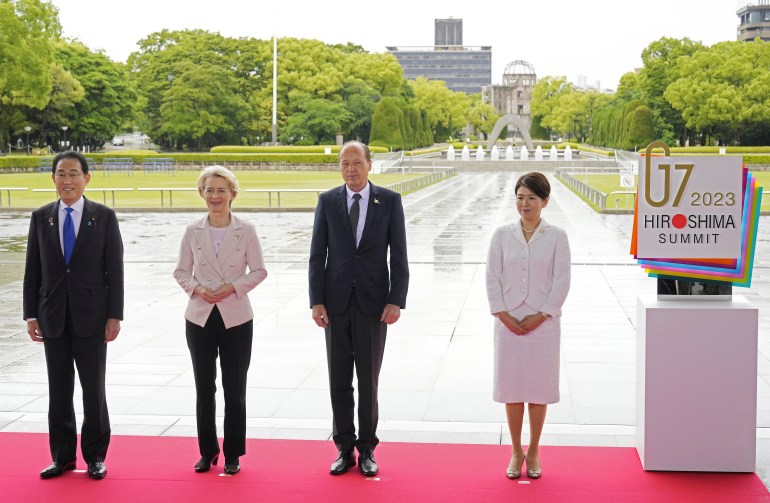 European Commission President Ursula von der Leyen (centre left) welcomed to the g& summit at the Hiroshima Peace Park by Japanese Prime Minister Fumio Kishida. He is standing on the left. Their respective spouses are on the right. The ruin of the A Bomb Dome is behind them.